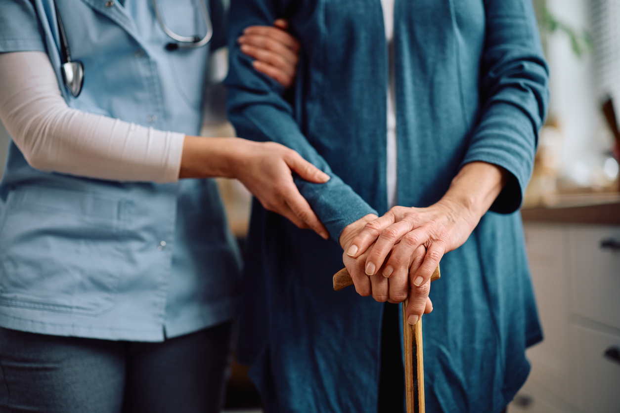 Close up of nurse guiding senior adult through home.