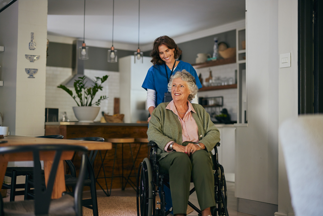 Nurse assists senior in wheelchair in home.