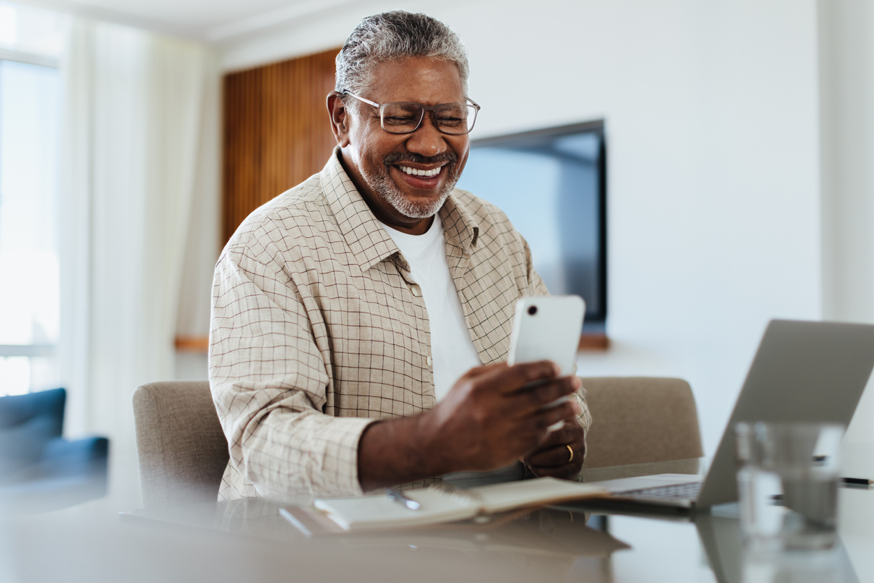 Mature man smiling at phone.