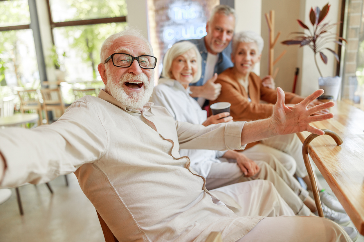 Senior adult man smiles as he paints on canvas.