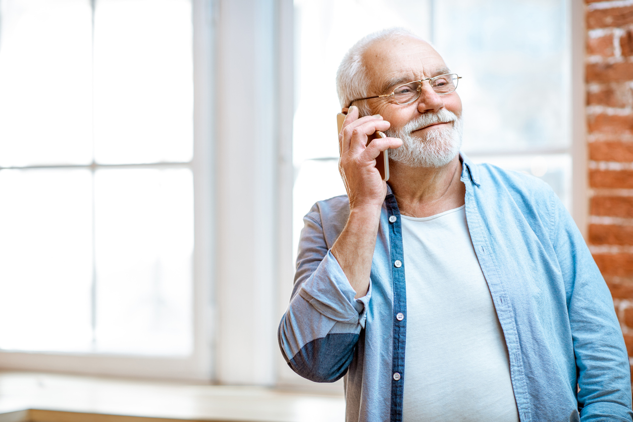 Mature man smiling while on phone.